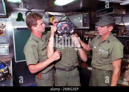 Électricien's Mate 3rd classe Stephen Wright, à gauche, et Boatswain's Mate 1st classe James Brady, à droite, aide électricien's Mate 3rd classe Shawn Bowman comme il est équipé d'un masque de plongeur Mark 3. Les trois plongeurs de la Marine sont des membres d'équipage à bord du destroyer-tendre USS YOSEMITE (AD-19), stationnés dans le golfe pendant les opérations d'interdiction maritime. Base : USS Yosemite (AD 19) Banque D'Images