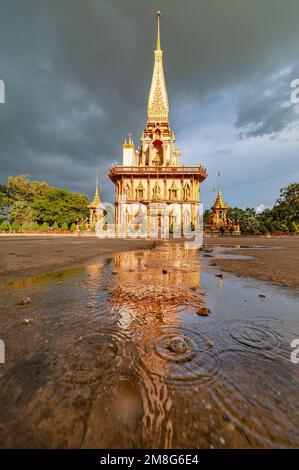 De belles gouttes de pluie dorées et des ondulations d'eau avec reflet du temple de Chasthararam (Wat Chalong). Le temple est le monument historique de Phuketใ Banque D'Images