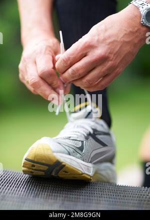 Se préparer à son jogging. Gros plan coupe courte image d'un jogging qui fixe les lacets à ses chaussures de course à pied. Banque D'Images
