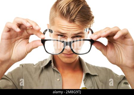 Effort vers À plus. Portrait studio d'un jeune homme qui s'accroupse à travers une paire de lunettes qu'il tient devant lui. Banque D'Images