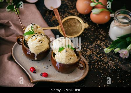 Glace à la vanille maison servie sur une assiette heratée, décorée d'œufs et de deux coccinelles. Banque D'Images