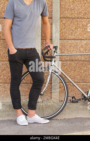 Comme mes roues. un jeune homme élégant debout à côté d'un vélo. Banque D'Images