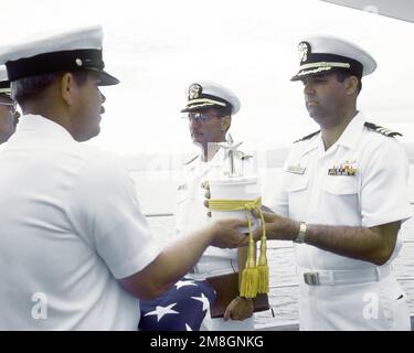 Le MCPO Charles Cartwright présente l'urne contenant les restes du CDR Harold Schwartz au CDR Robert James, commandant du navire-citerne USS RACINE, lors de l'enterrement en mer pour le médecin retraité de la Marine. Schwartz a été médecin affecté au bataillon de parachutistes, 1st Division Marine, et a participé à des opérations de combat sur Guadalcanal, les îles Gilbert, les îles Marshall et Okinawa. La RACINE est ancrée à Iron Bottom Sound au large de Guadalcanal pendant la cérémonie. Pays : Océan Pacifique (POC) Banque D'Images
