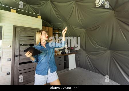 femme avec une tablette qui active le système de ventilation comme récupérateur pour la qualité de l'air frais à l'intérieur, maison intelligente Banque D'Images