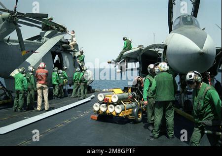 Les membres de l'équipage du pont de vol sont au service d'un hélicoptère de l'escadron anti-sous-marin 12 (HS-12) SH-3H Sea King sur le pont de vol du porte-avions USS Independence (CV-62) alors que le transporteur est en cours dans le golfe pendant l'opération Southern Watch, Un effort multinational visant à établir une zone d'exclusion aérienne pour les avions iraquiens au sud du prallèle de 32nd en Irak. D'autres membres d'équipage se trouvent à côté d'un F-14A Tomcat et d'une unité de service d'azote NAN-2, à droite. Sujet opération/série: SUD PAYS DE VEILLE: Inconnu Banque D'Images