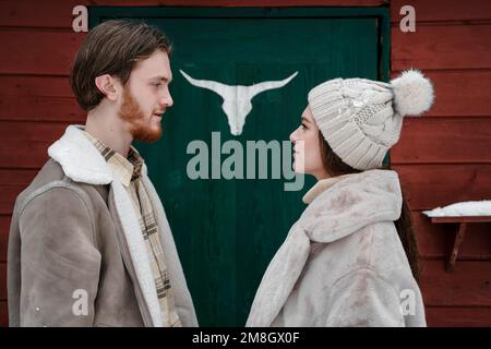 Une petite fille qui marche près de la grange rouge, porte verte. Deer,elk,bull bois.Snowy froid hiver dans la campagne.Skating,avoir du plaisir,rire.vêtements élégants, Banque D'Images