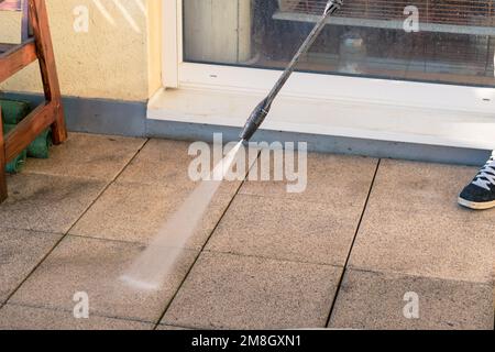 homme avec la terrasse de nettoyage de tube avec la pression de l'eau de la saleté Banque D'Images