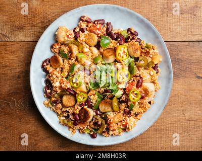 Assiette avec un Jambalaya de riz au chou-fleur et des saucisses végétaliennes. Banque D'Images