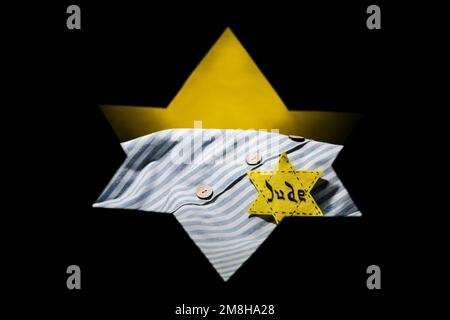 Uniforme de prisonnier et badge juif visibles à travers la forme de l'étoile David sur fond sombre. Journée internationale de commémoration de l'Holocauste Banque D'Images