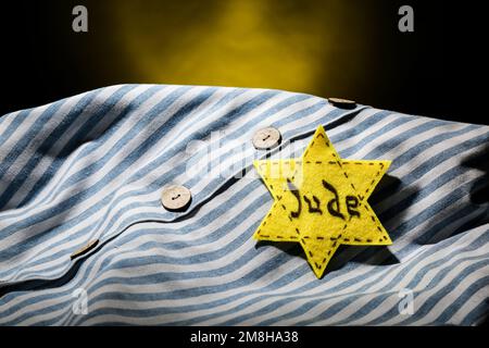 Uniforme de prisonnier et badge juif sur fond sombre, gros plan. Journée internationale de commémoration de l'Holocauste Banque D'Images