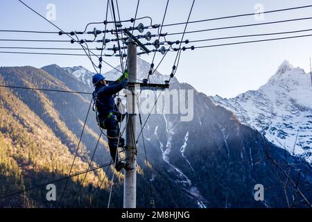 (230114) -- DEQEN, 14 janvier 2023 (Xinhua) -- Wangden inspecte les lignes de transport d'électricité dans le village de Yubeng, comté de Deqen, dans le sud-ouest de la province du Yunnan en Chine, 9 janvier 2023. Wangden, 34 ans, est le directeur associé de la branche Yunnan de la centrale électrique Yanmen de China Southern Power Grid, dans le comté de Deqen. En 2015, il a été affecté à la charge des tâches d'entretien à Yubeng, un village local situé au pied de montagnes enneigées. En tant que travailleur de l'alimentation électrique le plus longtemps au service de Yubeng, l'homme a été témoin de changements énormes dans le village. Dans le passé, Yubeng a été pratiquement coupé de la Banque D'Images