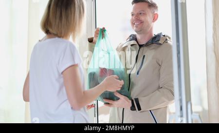 Un messager souriant livrant des articles d'épicerie à une femme à la maison Banque D'Images