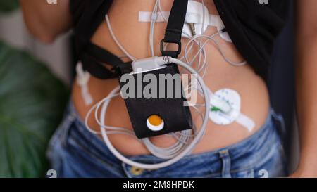 Femme équipée d'un moniteur Holter pour la surveillance quotidienne de l'électrocardiogramme et de la pression artérielle. Banque D'Images