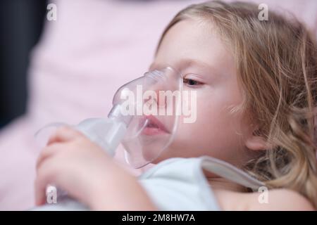 Masque à oxygène de la petite fille mignonne sur le visage sur le lit à l'hôpital Banque D'Images