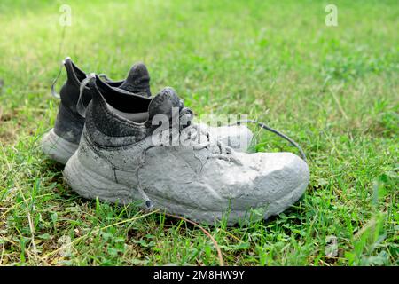 Chaussures fortement tachées dans la peinture grise sur l'herbe verte Banque D'Images