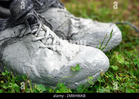 Chaussures fortement tachées dans la peinture grise sur l'herbe verte Banque D'Images