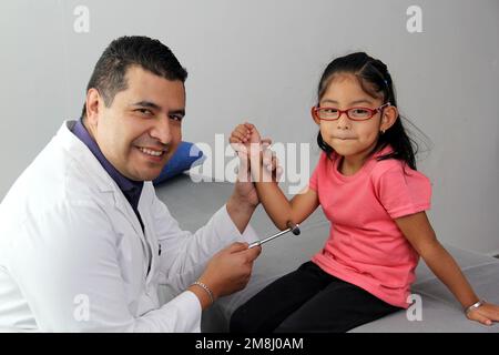 Latino médecin medic et jeune patient dans le bureau médical vérifie ses réflexes sur le marteau dans son examen pour trouver le diagnostic de la maladie Banque D'Images