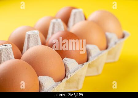 Faites dorer les œufs frais dans un contenant à œufs sur fond jaune.Ingrédients pour la cuisson.Une saine alimentation est un concept.Orientation horizontale, Banque D'Images