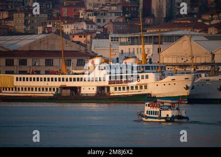 un petit bateau passe devant des navires en réparation au coucher du soleil Banque D'Images