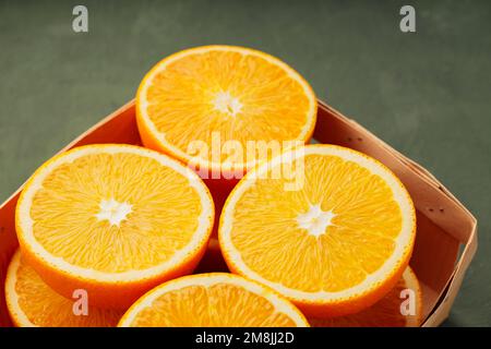 Moitiés d'oranges dans une boîte en bois. Gros plan sur les oranges fraîches et juteuses Banque D'Images