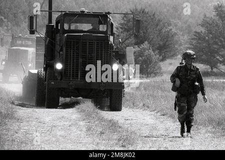 Soldat de la compagnie de transport 1158th, Monroe, W.I., pratique les mouvements de convoi de véhicules pendant l'entraînement de Lanes '94. Un soldat sur la droite marche en plein équipement de combat, fusil M16 inclus, comme un camion de cinq tonnes approche de l'arrière. Base: Fort McCoy État: Wisconsin (WI) pays: Etats-Unis d'Amérique (USA) Banque D'Images