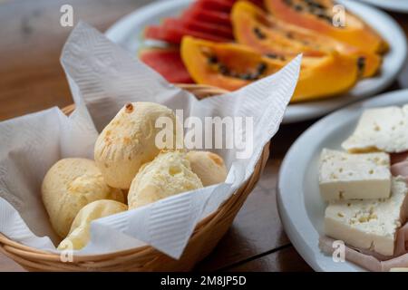 Petit déjeuner brésilien avec fromage Minas (queijo minas), pain au fromage (Pão de queijo) servi avec des fruits, sous lumière naturelle, tak photo réaliste Banque D'Images