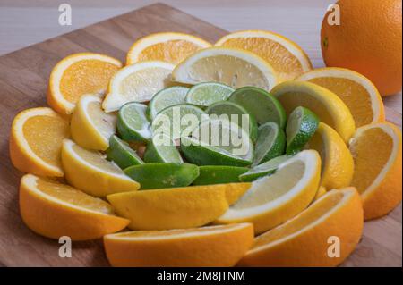 Des quartiers d'orange, de citron et de lime sur une planche à découper en bois. Banque D'Images