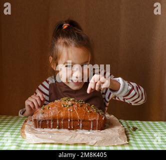 Une petite fille décorera un cupcake le saupoudrer de graines dans la cuisine à la maison. Banque D'Images