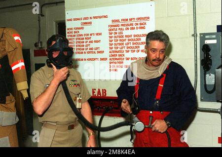LE CHEF DU bateau MAÎTRE DE L'électricien PRINCIPAL (EMCM) Schmidt donne un masque de respiration d'urgence (EBD) tandis que le Machinist Mate First Class (MM1) Pex montre comment accrocher un EAB au manifold. Base: O'Kane STF, San Diego État: Californie (CA) pays: Etats-Unis d'Amérique (USA) Banque D'Images