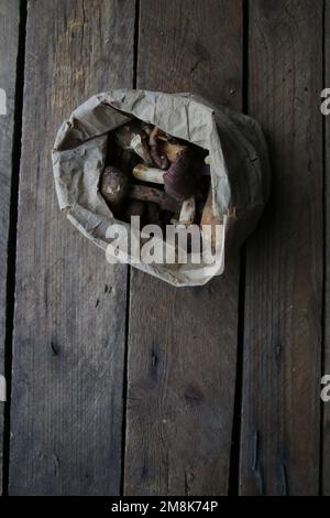 Champignons dans un sac en papier sur une table ancienne. Banque D'Images