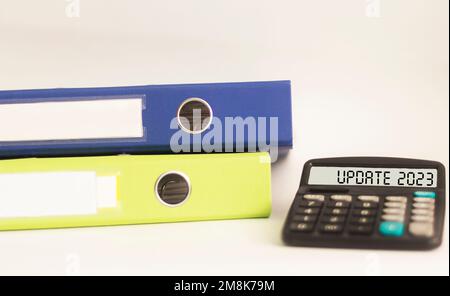 MISE À JOUR du texte 2023 sur l'écran de la calculatrice et fond blanc avec dossiers de documents Banque D'Images