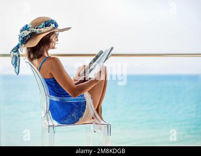 vue détaillée d'une femme dans un chapeau assis sur la terrasse d'un hôtel lisant un magazine. concept vacances sur la côte espagnole. Banque D'Images