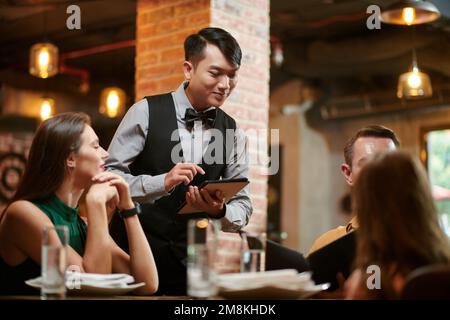 Serveur de restaurant souriant prenant la commande de la famille Banque D'Images