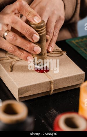 CRAFTSMAN met un timbre sur la cire d'étanchéité sur les cadeaux faits à la main dans l'atelier. Procédé de scellement de cire sur l'emballage cadeau en atelier Banque D'Images