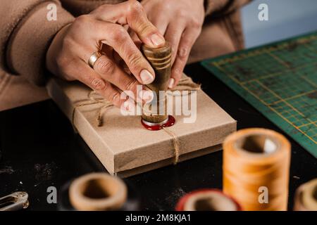 CRAFTSMAN met un timbre sur la cire d'étanchéité sur les cadeaux faits à la main dans l'atelier. Procédé de scellement de cire sur l'emballage cadeau en atelier Banque D'Images