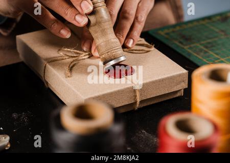 CRAFTSMAN met un timbre sur la cire d'étanchéité sur les cadeaux faits à la main dans l'atelier. Procédé de scellement de cire sur l'emballage cadeau en atelier Banque D'Images