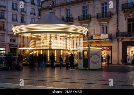 Montpellier, Occitanie, France, 12 28 2022 - Carousel la nuit sur la place de la Comédie, place de la Comédie avec des maisons historiques et des gens qui attendent Banque D'Images