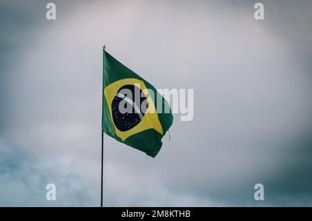 Drapeau brésilien agitant dans un poteau avec ciel nuageux. Banque D'Images