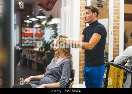 beau coiffeur de toucher les cheveux mouillés de son client avant de sécher, moyen-plein coup. Photo de haute qualité Banque D'Images