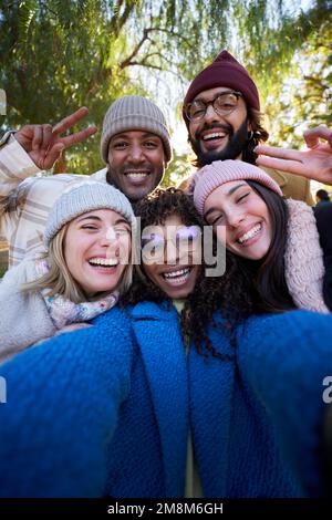 Verticale. L'hiver, le selfie souriant d'un groupe heureux d'amis multiculturels regardant l'appareil photo Banque D'Images