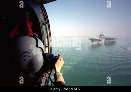 Vue de derrière la US Navy Photographer's Mate 3rd classe (PH3) Mark Hamilton prenant des photos aériennes du porte-avions de LA US Navy KITTY HAWK CLASSE USS KITTY Hawk (CV 63). Le KITTY HAWK quitte la base navale de San Diego, sur le chemin d'un déploiement de six mois dans le Pacifique occidental. Vue de derrière la US Navy Photographer's Mate 3rd classe (PH3) Mark Hamilton prenant des photos aériennes du porte-avions de LA US Navy KITTY HAWK CLASSE USS KITTY Hawk (CV 63). Le KITTY HAWK quitte la base navale de San Diego, sur le chemin d'un déploiement de six mois dans le Pacifique occidental. Banque D'Images