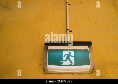 Panneau de sortie de secours de l'homme en marche sur un mur sale Banque D'Images