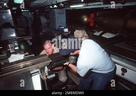 Un chef de la petite garde supervise un collègue d'équipage dans la salle des torpilles de l'USS Gurnard (SSN-662) à propulsion nucléaire alors qu'ils ajustent les rails de transport des torpilles. Base : San Diego Harbour État : Californie (CA) pays : États-Unis d'Amérique (USA) Banque D'Images