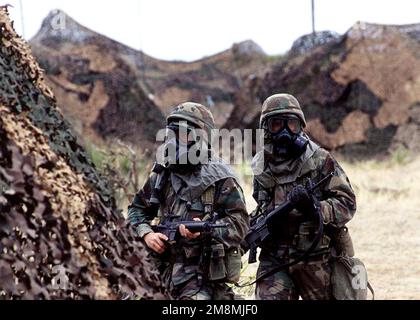 Deux soldats de l'armée américaine, portant le masque chimique et biologique M40A1, affectés au quartier général et à la batterie du quartier général, 32nd Bataillon, 31st Brigade d'artillerie de défense aérienne, examinent leur camp après une simulation d'attaque chimique aérienne contre leur camp sur la chaîne McGregor, fort Bliss, Texas. Les attaques chimiques (non illustrées) sont exécutées par des hélicoptères russes exploités par des membres du Commandement de l'essai et de l'évaluation de l'opération, activité de soutien aux menaces à l'aérodrome de l'Armée de Biggs, au Texas, en appui à l'exercice ROVING SANDS '97, 21 avril 1997. Objet opération/série: ROVING SANDS '97 base: Fort Bliss État: Texas (T Banque D'Images