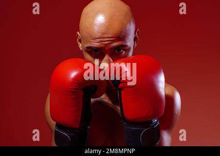Portrait d'un sportif portant des gants de boxe pratiquant le combat sur fond de studio Banque D'Images
