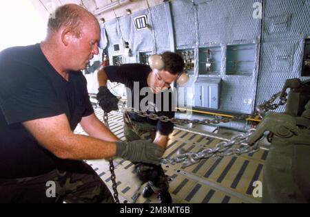 PERSONNEL SGT. Ronald L. Coward et LE PERSONNEL SGT. Jason P. Woodman, les superviseurs de la mobilité du transport aérien affectés au vol de mobilité du port aérien de 437th, base aérienne de Charleston, S.C., utilisent des chaînes d'arrimage pour fixer un camion au pont d'une galaxie C-5 à l'aéroport international Cheddi Jagan, Timehri. Les camions ont été utilisés par les participants à New Horizon '97, premier exercice d'assistance humanitaire et civique combiné mené entre les États-Unis et le Guyana. Des militaires de la Force aérienne, de la Réserve de la Force aérienne et de la Garde nationale, de l'Armée de terre, de la Garde nationale de l'Armée de terre et du corps des Marines ont participé au Banque D'Images