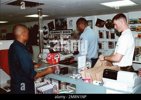 LE caporal Aaron R. Arrington du corps des Marines DES ÉTATS-UNIS (HMM-264), de Helicopter Marine Medium-264, effectue un achat auprès du Serviceman du navire de la Marine des États-Unis de deuxième classe Melvin L. Thomas au magasin du navire à bord de l'USS WASP (LHD 1). LE CPL Ronald R. Lavelle, de S-1, quartier général et Compagnie de services, équipe de débarquement du bataillon 3/2, aide à l'ensachage. Ces Marines et marins sont déployés avec l'unité expéditionnaire maritime de 26th dans le cadre de la Sixième flotte de la Force d'atterrissage. Base : USS Wasp (LHD 1) Banque D'Images