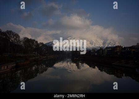 Srinagar, Inde. 14th janvier 2023. Vue sur la rivière Jhelum et la neige couvrait les collines de Zabarwan pendant une journée ensoleillée après une chute de neige fraîche à Srinagar. Le bureau météorologique a prévu un temps sec au Cachemire jusqu'à 14-18 janvier. Crédit : Pacific Press Media production Corp./Alay Live News Banque D'Images