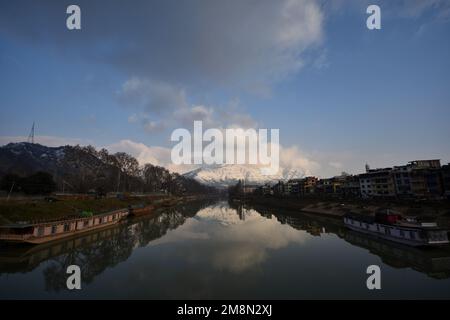 Srinagar, Inde. 14th janvier 2023. Vue sur la rivière Jhelum et la neige couvrait les collines de Zabarwan pendant une journée ensoleillée après une chute de neige fraîche à Srinagar. Le bureau météorologique a prévu un temps sec au Cachemire jusqu'à 14-18 janvier. Crédit : Pacific Press Media production Corp./Alay Live News Banque D'Images