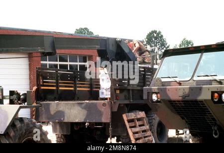 Un membre du bataillon de soutien de 230th, la Garde nationale de Caroline du Nord dirige l'exploitant du système d'Armée de sauvetage tout-terrain (ATLAS) de TRAK qui charge des fournitures sur un camion de 5 tonnes pour distribution dans les régions dévastées de l'État après l'ouragan Bonnie. Base: Kinston État: Caroline du Nord (NC) pays: Etats-Unis d'Amérique (USA) Banque D'Images